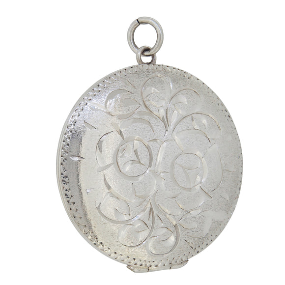 A modern, silver, circular locket with an engraved floral pattern