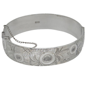 A mid-20th century, silver, hinged bangle with engraved floral decoration to the front.