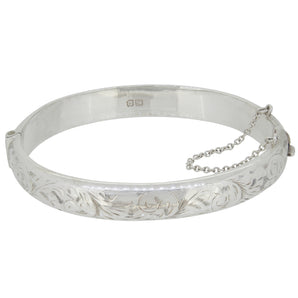 A mid-20th century, silver, hinged bangle with an engraved foliate design.