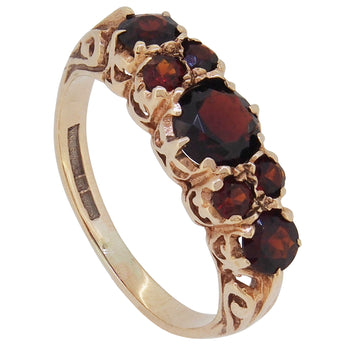 A modern, 9ct yellow gold, garnet set, seven stone half hoop ring.