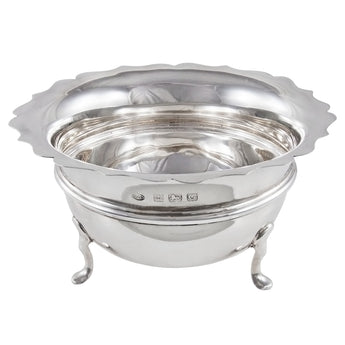 An early 20th century, silver, circular sweet bowl with a scalloped rim on three feet.