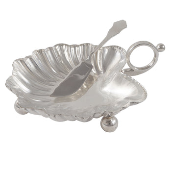 A Victorian, silver, shell shaped butter dish on three ball feet & ring handle, a clear glass liner & a silver butter knife.