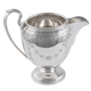 An early 20th century, silver cream jug with engraved ribbon & swag decoration, scroll handle & a pedestal foot.
