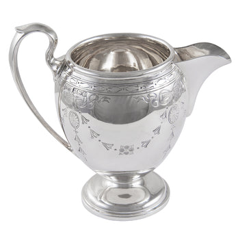 An early 20th century, silver, engraved cream jug with ribbon decoration on a pedestal foot.