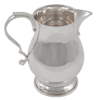 A mid-20th century, silver cream jug on a pedestal foot.