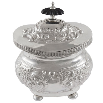 An Edwardian, silver tea caddy with foliate & scroll decoration, a fluted border, ebonised finial & four ball feet.