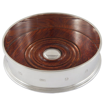 A modern, silver & wood decanter coaster.
