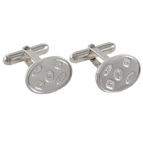 A pair of modern, silver, oval, toggle link cufflinks with feature hallmarks