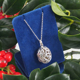 A modern, silver, oval locket with a pierced front & chain.