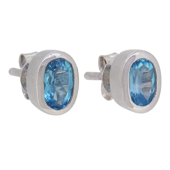 A pair of modern, silver, blue topaz set stud earrings