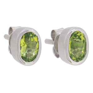 A pair of modern, silver, peridot set stud earrings