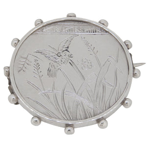 An Edwardian, silver, Aesthetic, circular brooch featuring a bird & grass