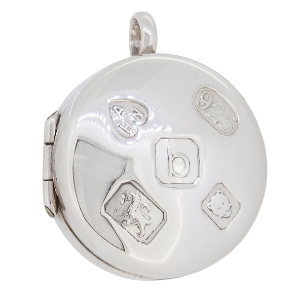 A modern, silver circular box locket with feature hallmarks