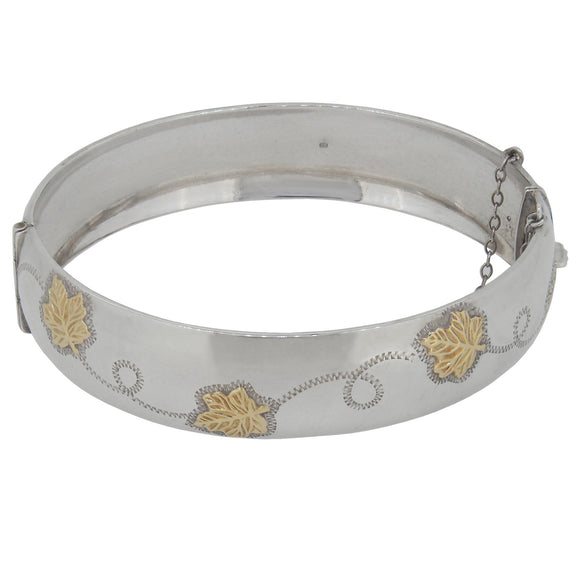 A modern, silver, half engraved, hinged bangle with applied leaves