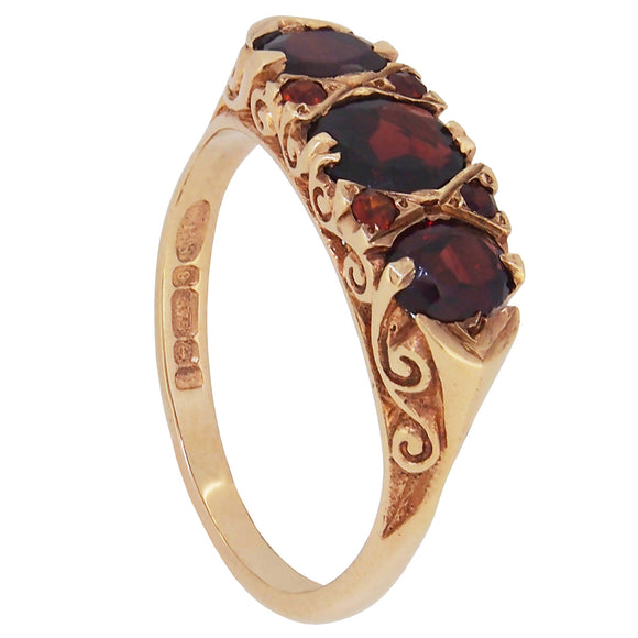 A modern, 9ct yellow gold, garnet set, seven stone, carved half hoop ring