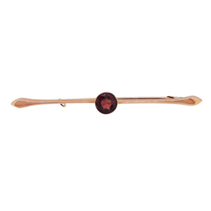 An early 20th century, 9ct rose gold, garnet set single stone bar brooch