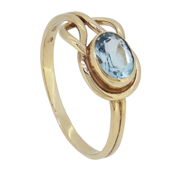 A modern, 9ct yellow gold, blue topaz set, single stone knot ring