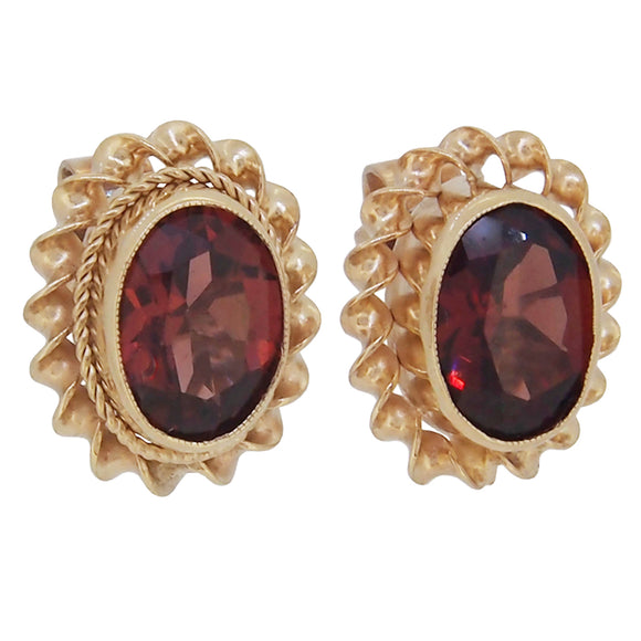 A pair of 9ct yellow gold, garnet set stud earrings with a cord border