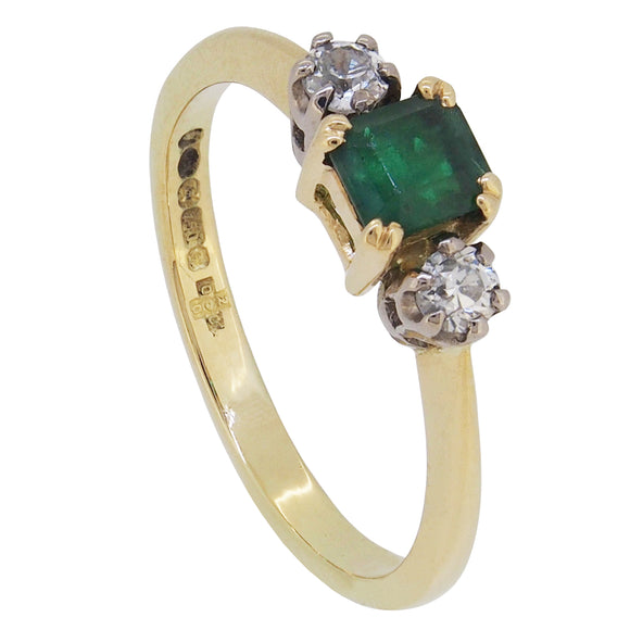 A modern, 18ct yellow gold, emerald & diamond set three stone ring.