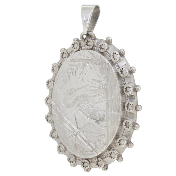 A Victorian, silver, Aesthetic movement, oval pendant featuring an image of a heron