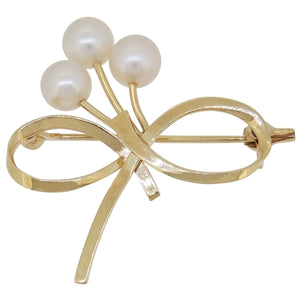 A mid-20th century, 14ct yellow gold, pearl set, three stone bow brooch.