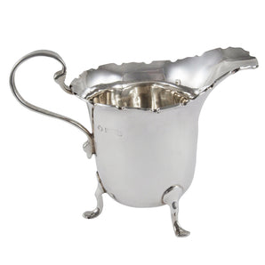 An early 20th century, silver cream jug with a scalloped rim, scroll handle & three cabriole feet.