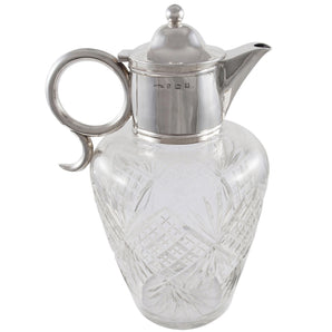 An Edwardian, glass, claret jug with a silver mount, lid, handle & spout.