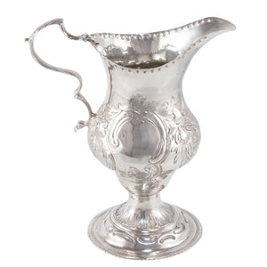 A Georgian, silver, chased cream jug on a pedestal