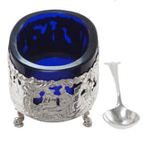 A Victorian, silver, open salt depicting a couple under a tree, with a blue glass liner & spoon