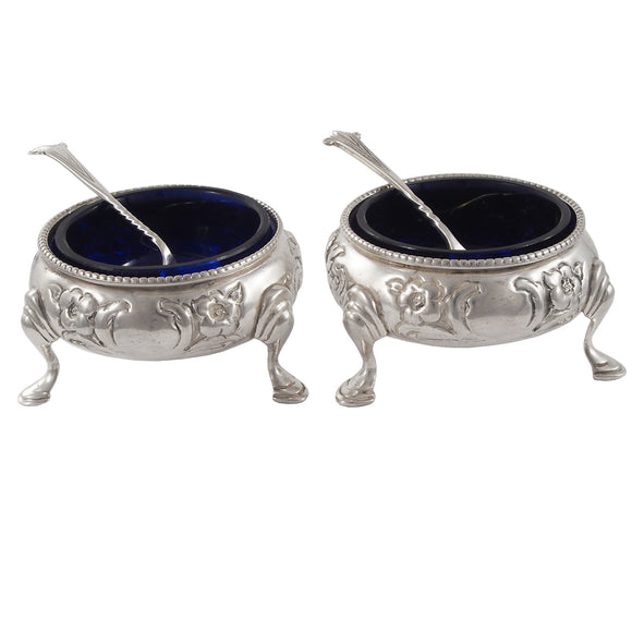 A pair of Victorian, silver, open salts on three feet, with blue glass liners & spoons
