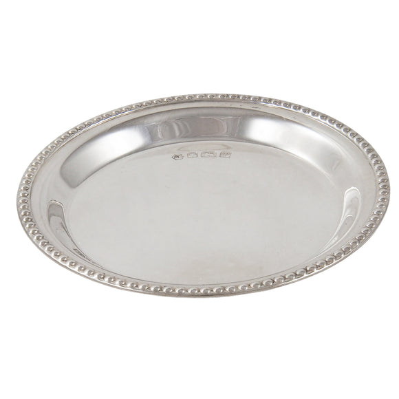 A modern, silver, circular pin tray with a bead edge