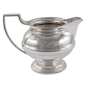 An Edwardian, silver cream jug on a pedestal foot with a reeded border.