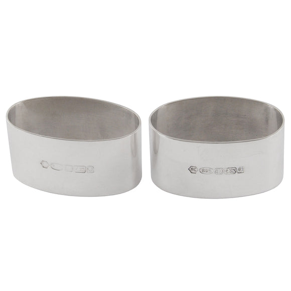 A pair of modern, silver, plain, oval napkin rings.