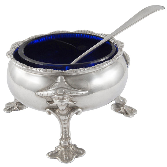 A Georgian, silver open salt on three feet with blue glass liner & spoon.