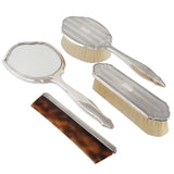 A modern, silver, four piece brush set