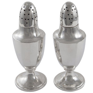 A pair of Edwardian, silver pepper pots on pedestal feet.